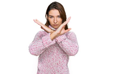 Kışın yün süveter giyen beyaz bir genç kız kollarını kavuşturup negatif işaret veriyor, kızgın surat yapıyor. 