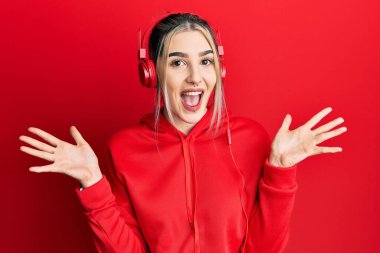 Spor kıyafetleri giyen, kulaklık takan, çılgın kutlamalar yapan, kollarını kaldırıp heyecanla haykıran genç ve modern bir kız. Kazanan konsept 