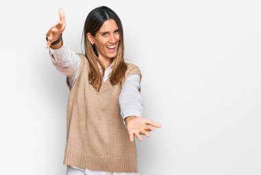 Sıradan kıyafetler giymiş genç bir kadın kameraya bakıyor ve sarılmak için kollarını açmış gülümsüyor. Mutluluğu kucaklayan neşeli bir ifade.. 