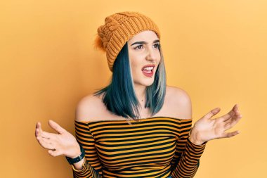 Genç, modern bir kız yün şapka takıyor, deli gibi bağırıyor, bağırıyor, agresif bir ifade ve kollarla bağırıyor. hüsran kavramı. 