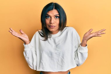 Genç Latin transseksüel kadın gündelik giysiler giyiyor, habersiz ve kolları açık, hiçbir fikrim yok ve şüpheli bir yüzüm var.. 