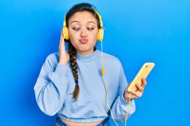 Akıllı telefon ve kulaklık kullanan genç İspanyol kız balık suratlı ve şaşı gözlü, çılgın ve komik.. 