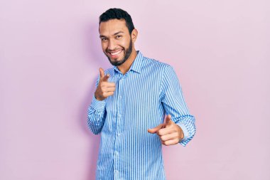 Sakallı, sıradan mavi gömlekli, neşeli ve komik yüzlü İspanyol bir adam kamerayı işaret ediyor. iyi enerji ve titreşimler. 