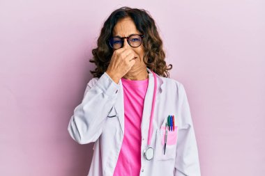 Orta yaşlı İspanyol kadın doktor üniforması giyiyor ve gözlük takıyor. Kokuşmuş ve iğrenç bir koku alıyor. Dayanılmaz bir koku. Kötü kokuyor. 