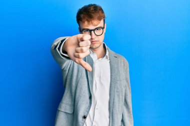 Zarif kıyafetler ve gözlük takan genç beyaz adam mutsuz ve kızgın görünüyor. Reddedilmiş ve olumsuz bir hareket yapıyor. kötü ifade. 