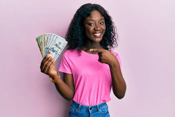 Hermosa Mujer Joven Africana Sosteniendo Dólares Sonriendo Feliz Señalando Con — Foto de Stock