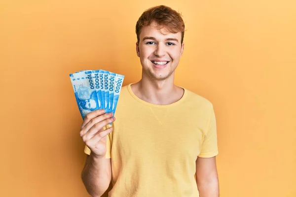 Młody Biały Mężczyzna Trzymając Meksykańskie Peso Patrząc Pozytywnie Szczęśliwy Stojąc — Zdjęcie stockowe