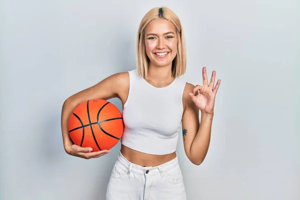 漂亮的金发碧眼的女子手握篮球 手握手签 笑容满面 表示友善的手势 是极好的象征 — 图库照片