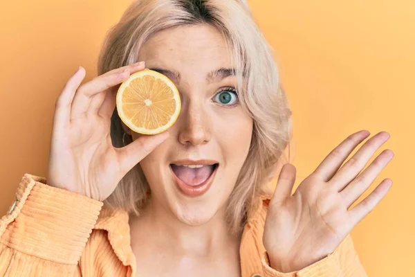 Mladá Blondýnka Drží Citron Přes Oko Slaví Úspěch Šťastným Úsměvem — Stock fotografie