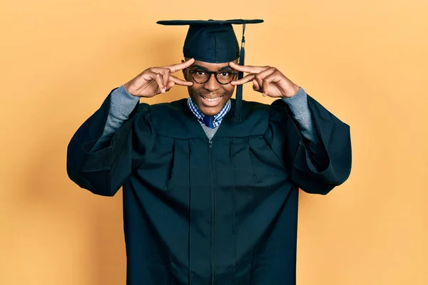 Młody Afroamerykanin Czapce Dyplomowej Szlafroku Robi Symbol Pokoju Palcami Twarzy — Zdjęcie stockowe