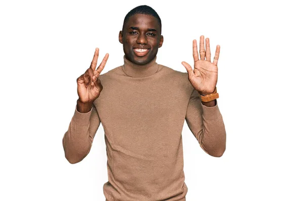 身穿休闲式冬季毛衣的年轻的非洲裔美国人露出七号手指 面带微笑 自信而快乐 — 图库照片