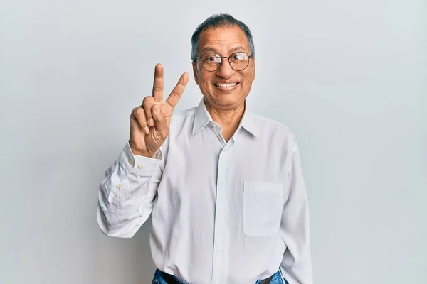 印度中年男子 身穿休闲装 戴着眼镜 手指头一指二指 面带微笑 自信而快乐 — 图库照片
