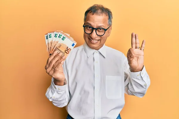 Hombre Indio Mediana Edad Sosteniendo Montón Billetes Euros Haciendo Signo —  Fotos de Stock