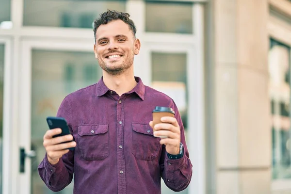 街でスマートフォンとコーヒーを飲んでいる若いヒスパニック系の男 — ストック写真