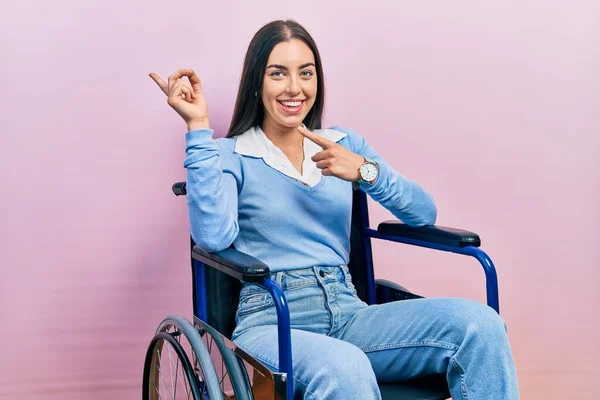車椅子に座って笑っている青い目の美しい女性とカメラを見て両手と指を横に向けて — ストック写真