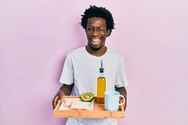 Joven Afroamericano Hombre Sosteniendo Bandeja Con Desayuno Comida Guiño Mirando —  Fotos de Stock