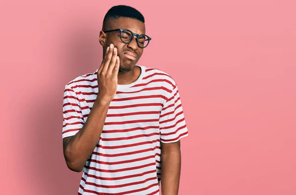 歯の痛みや歯の病気のために痛みを伴う表現で手で手に触れるシャツや眼鏡を着用若いアフリカ系アメリカ人男性 歯科医 — ストック写真