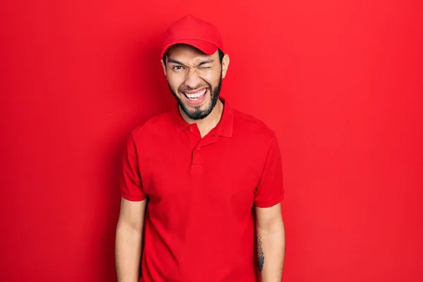 Hombre Hispano Con Barba Vistiendo Uniforme Entrega Gorra Guiñando Ojo —  Fotos de Stock