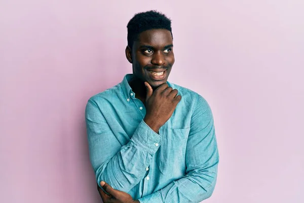 stock image Handsome black man wearing casual clothes with hand on chin thinking about question, pensive expression. smiling with thoughtful face. doubt concept. 