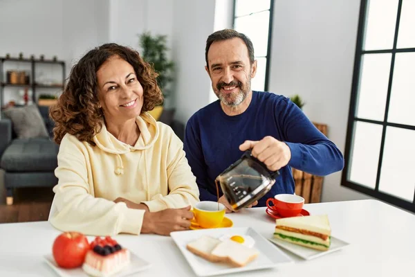 Pareja Hispana Mediana Edad Sonriendo Feliz Sentada Mesa Desayunando Casa —  Fotos de Stock