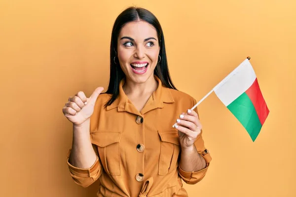 Joven Morena Sosteniendo Bandera Madagascar Apuntando Con Pulgar Hacia Lado —  Fotos de Stock