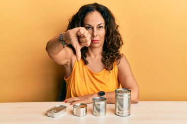 Kızgın suratlı, orta yaşlı, güzel bir kadın. Negatif işaretler, baş parmakları aşağıda, reddedilme konsepti. 