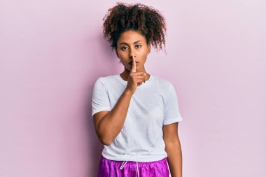 Afro saçlı, spor giysili güzel Afro-Amerikalı kadın sessiz olmak istiyor. sessizlik ve gizli konsept. 