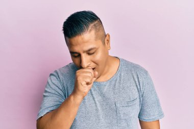 Günlük kıyafetler giyen genç latin adam kendini iyi hissetmiyor ve soğuk algınlığı veya bronşitin belirtisi olarak öksürüyor. sağlık hizmeti kavramı. 