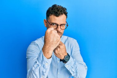 Gündelik kıyafetler ve gözlük takan İspanyol genç adam yumruk savunma hareketiyle dövüşmeye hazır kızgın ve üzgün bir yüz, sorundan korkuyor. 