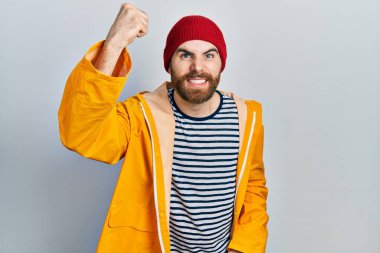 Sakallı, sarı yağmurluk giymiş, kızgın, kızgın, kızgın ve öfkeliyken öfkeyle bağıran beyaz bir adam. öfke ve agresif konsept. 