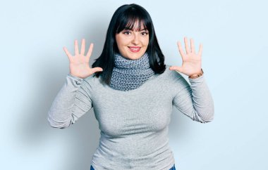 Kış eşarbı takan Latin kökenli genç bir kadın on numarayı gösterip işaret ederken kendinden emin ve mutlu bir şekilde gülümsüyor.. 