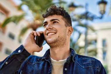 Genç İspanyol adam gülümsüyor. Şehirdeki akıllı telefondan konuşuyor.