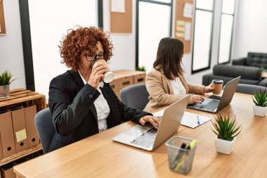 Ofiste çalışan iki kadın grubu. Olgun kadın ve Down sendromlu kız kapsayıcı takım çalışması yapıyor..
