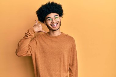 Afro saçlı, kışlık süveter giyen, telefonla el ve parmaklarıyla telefonla konuşan Afro-Amerikan genç adam. iletişim kavramları. 