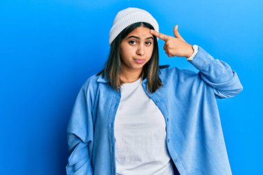 Alnındaki sivilceden mutsuz olduğunu gösteren sevimli yün şapkalı genç Latin kadın, siyah başlıklı çirkin enfeksiyon. sivilce ve deri problemi 