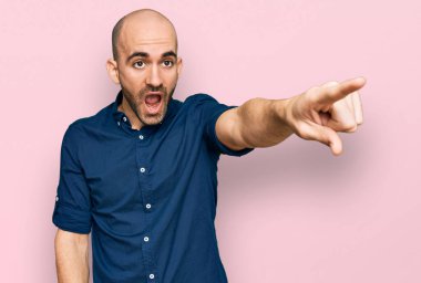 Gündelik giysiler giymiş genç İspanyol bir adam parmağıyla işaret ederek şaşırmış, ağzı açık, şaşırmış, ön tarafta bir şey var. 