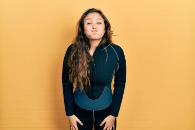Dalgıç neoprene üniforması giyen genç İspanyol kız komik yüzlü yanakları şişiriyor. Havayla şişmiş ağız, çılgın bir ifade.. 