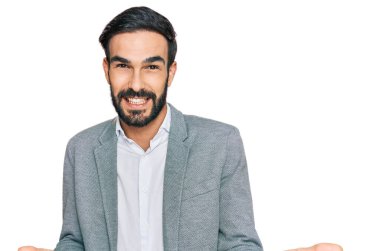 İş kıyafetleri giymiş genç bir İspanyol güler yüzlü, kolları açık, dostça bir hoş geldin, olumlu ve kendinden emin selamlaşma. 