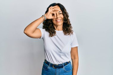 Orta yaşlı İspanyol kadın, günlük beyaz tişört giyiyor. El hareketi yapıyor. Gülümsüyor.. 