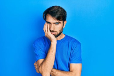 Günlük kıyafetler giyen genç İspanyol adam kollarını kavuşturarak depresyondan sıkılmış ve yorgun görünüyor.. 