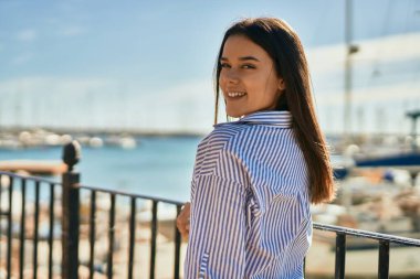 Genç İspanyol kız gülümseyerek şehirde mutlu mesut dikiliyor..