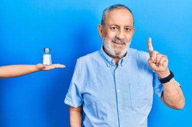 Sakallı yakışıklı kıdemli bir adam bir fikir sunuyor ya da sorguluyor, mutlu bir yüzle işaret ediyor. 