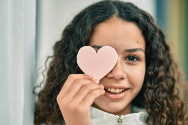 İspanyol genç kız gülümsüyor. Mutlu bir şekilde kalbi gözünün önünde tutuyor..