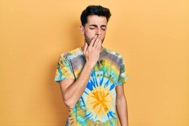 Gündelik kıyafetler giyen genç İspanyol adam ağzıyla ağzını kapatmaktan sıkılmış. Huzursuz ve uykulu.. 