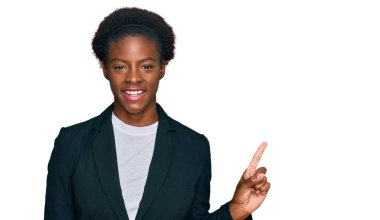 Genç Afro-Amerikan kız iş kıyafetleri içinde yüzünde kocaman bir gülümsemeyle, kameraya el ile işaret ederek bakıyor.. 
