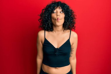 Kolsuz tişörtlü, sıradan giyinen genç İspanyol kadın dudaklı balık suratı yapıyor, çılgınca ve komik bir jest. Komik ifade. 