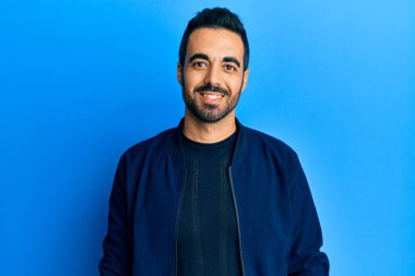 Yüzünde mutlu ve havalı bir gülümseme olan sıradan kıyafetler giyen genç İspanyol bir adam. şanslı kişi. 