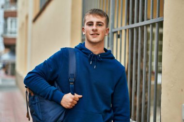 Üniversitede mutlu bir şekilde gülümseyen genç sarışın öğrenci..