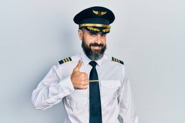 Uçak pilotu üniforması giyen İspanyol genç adam elleriyle mutlu bir jest yapıyor. Kameraya bakıp başarıyı gösteren ifade. 