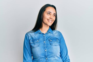 Sıradan kot ceket giyen genç İspanyol kadın yüzünde gülümsemeyle yan yana bakıyor, doğal bir ifade. Kendinden emin gülen. 